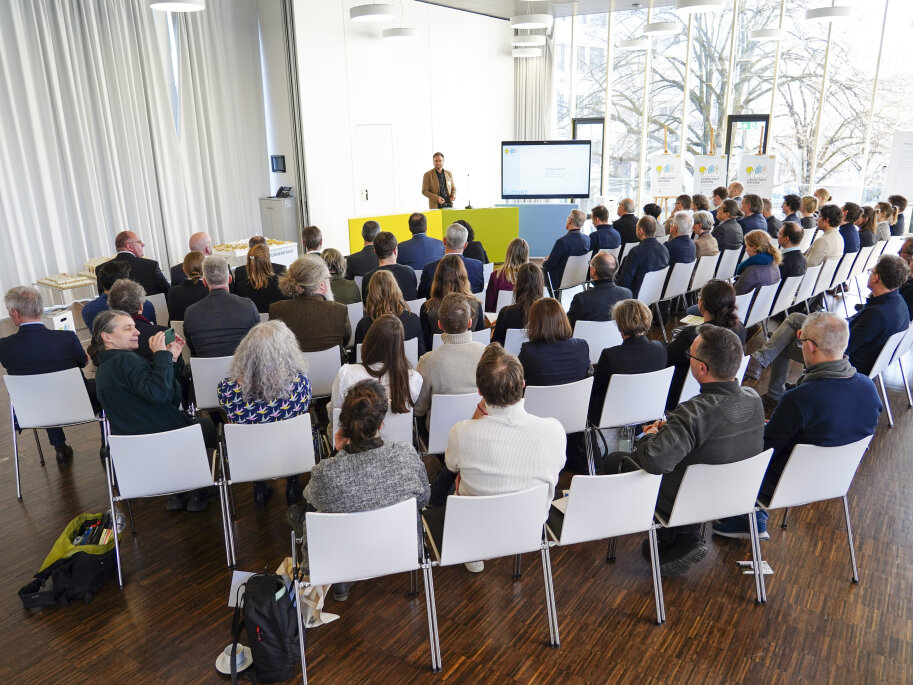 Viele Teilnehmende der Abschlussveranstaltung LANDSTADT BAYERN sitzen im Plenum.